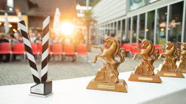 Die Trophäen, das Goldene Einhorn, stehen auf einem Tisch vor den Zuschauerreihen beim Alpinale Kurzfilmfestival bereit. | © Anna Salcher
