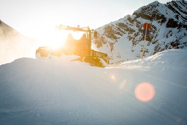 PistenBully in der Sonne | © Bergbahnen Brandnertal, Michael Marte Das Gegenlicht strahlt in den PistenBully während die Piste präpariert wird. | © Bergbahnen Brandnertal, Michael Marte