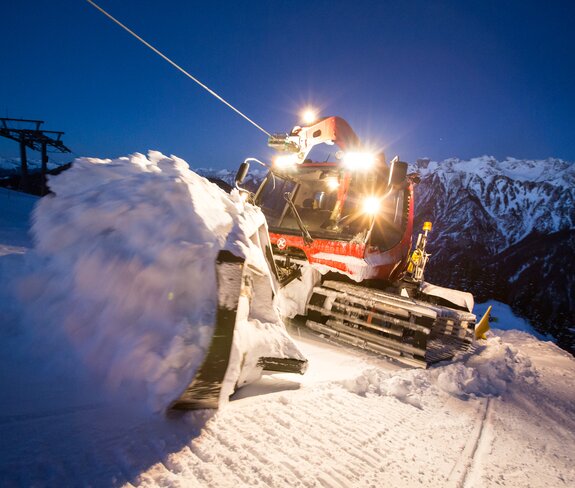 PistenBully am Seil schiebt Schneemasse | © Bergbahnen Brandnertal, Michael Marte Der Kässbohrer mit Winde hängt am Windenseil und schiebt Schnee im Schild nach oben. | © Bergbahnen Brandnertal, Michael Marte