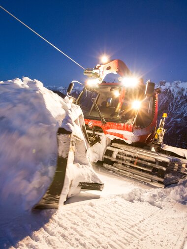 Der Kässbohrer mit Winde hängt am Windenseil und schiebt Schnee im Schild nach oben. | © Bergbahnen Brandnertal, Michael Marte